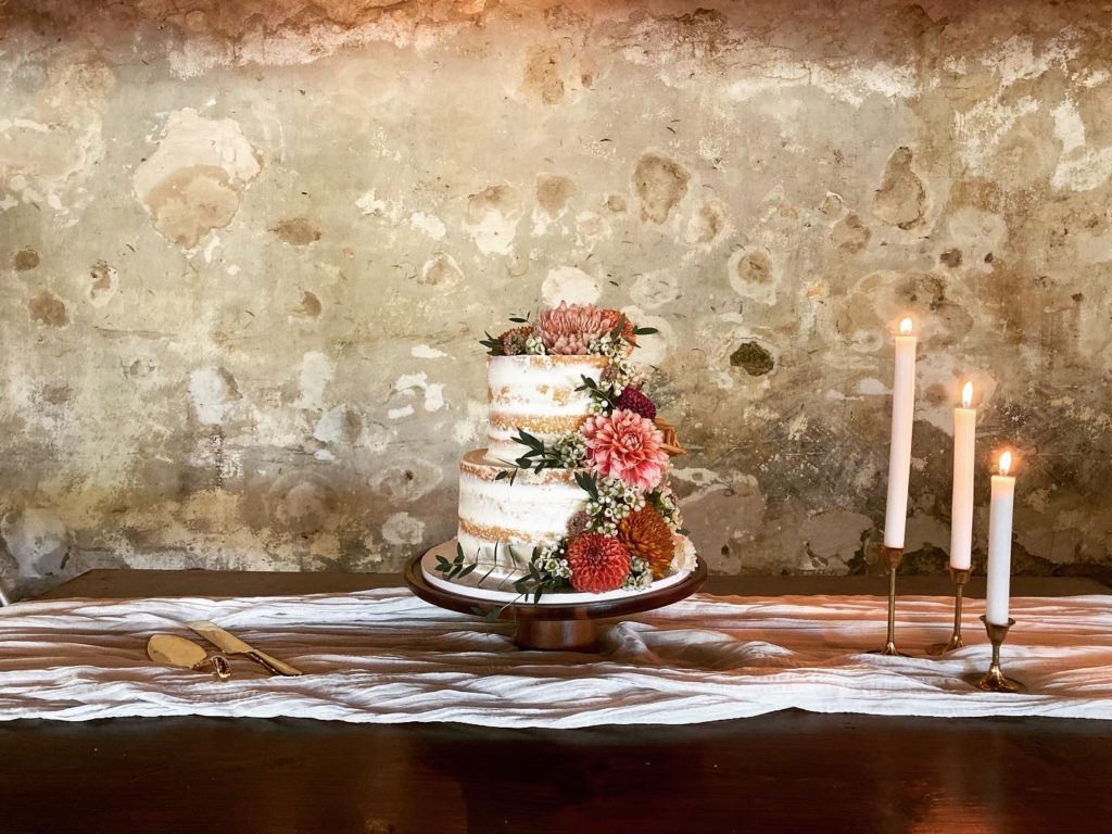 Wedding cake in a barn with cascading fresh flowers