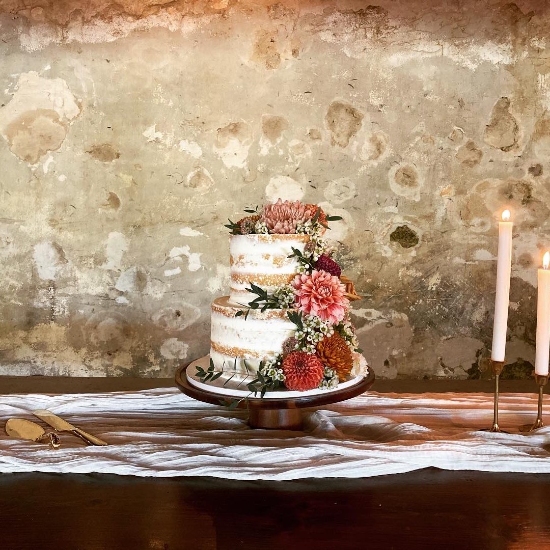 Wedding cake in a barn with cascading fresh flowers